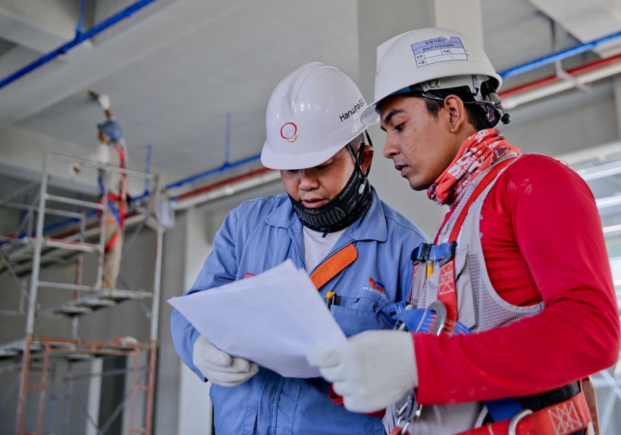 Two service professionals in hard hats reviewing job details on site